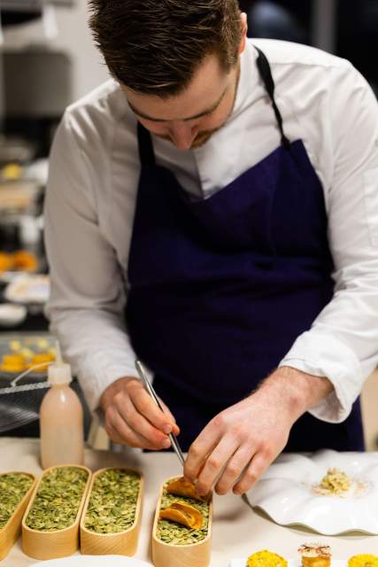 Préparation culinaire au Domaine du Liziec, chef en cuisine avec ingrédients et ustensiles sur le plan de travail