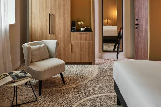 Espace détente d’une chambre du Domaine du Liziec à Vannes avec fauteuil design et mobilier en bois clair