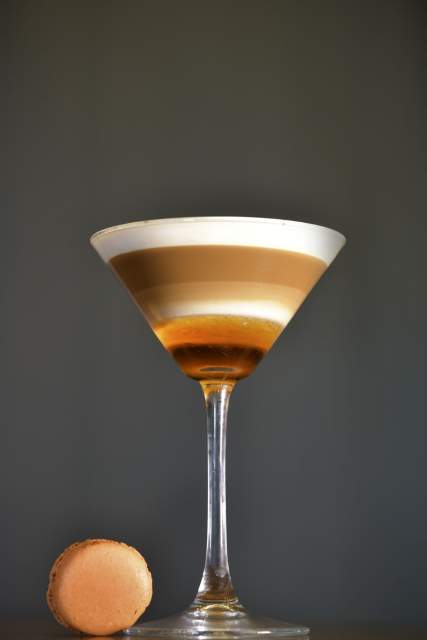 Cocktail en verre à martini au Domaine du Liziec, boisson en couches colorées sur fond sombre mettant en valeur son élégance