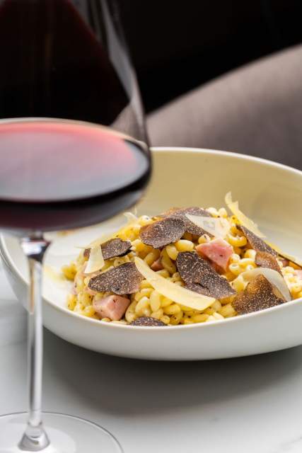 Pâtes gourmandes au Domaine du Liziec avec truffe, fromage râpé et jambon, accompagnées d’un verre de vin rouge