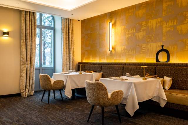 Salle de restaurant <span><span><span><span>1 Étoile Michelin </span></span></span></span>du Domaine du Liziec avec tables dressées, chaises modernes et décoration dorée dans une ambiance élégante et lumineuse