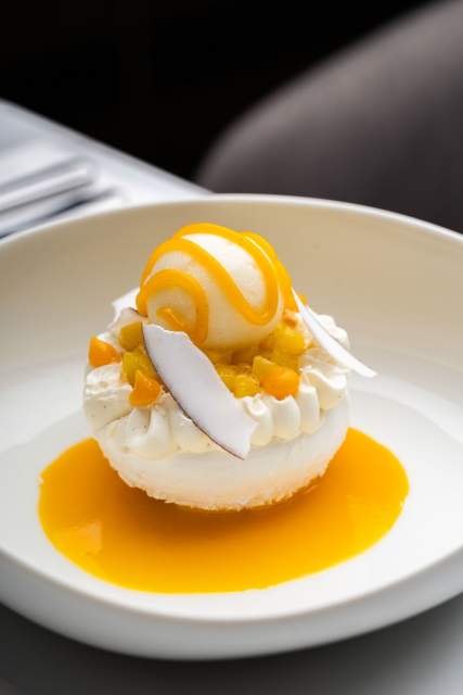 Dessert exotique au Domaine du Liziec avec fruits frais, crème fouettée, glace et sauce coco-mangue dans une présentation raffinée