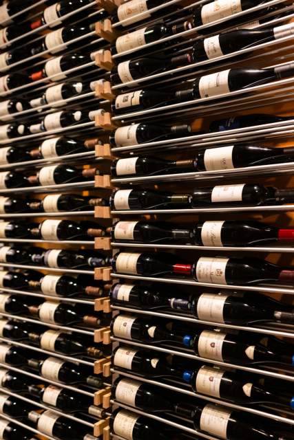 Cave à vins du Domaine du Liziec avec bouteilles soigneusement rangées sur racks métalliques dans une ambiance chaleureuse