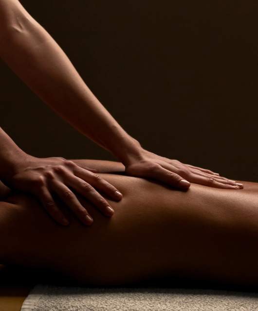 Massage relaxant au Domaine du Liziec, mains expertes sur le dos dans une ambiance apaisante et chaleureuse