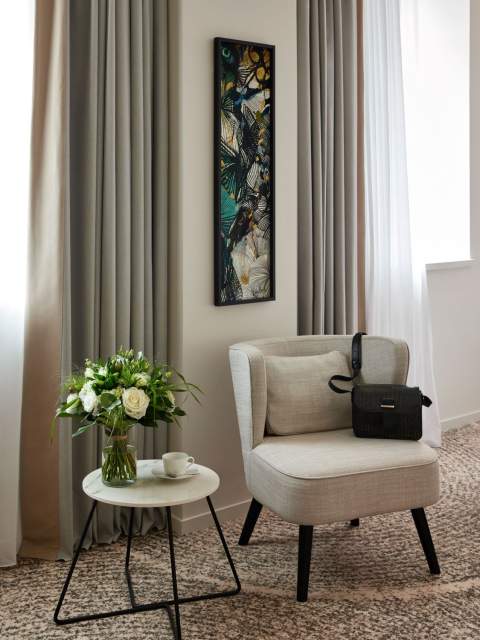 Coin détente du Domaine du Liziec avec fauteuil clair, table fleurie, lumière naturelle et décoration élégante