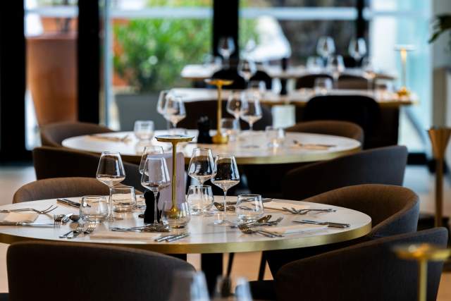 Table de restaurant gastronomique <span><span><span><span>1 Étoile Michelin </span></span></span></span>soigneusement dressée au Domaine du Liziec, avec verrerie élégante, décoration raffinée et vue sur la verdure extérieure