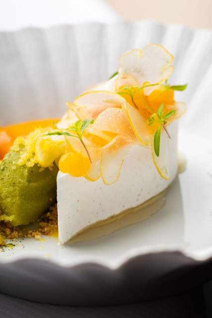 Dessert raffiné au Domaine du Liziec, mousse à cœur vert garnie de fruits jaunes et herbes fraîches sur assiette élégante