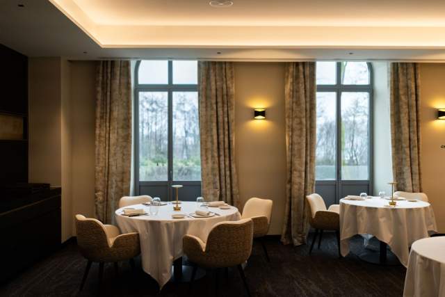 Salle de restaurant <span><span><span><span>1 Étoile Michelin </span></span></span></span>du Domaine du Liziec avec tables rondes, chaises confortables et lumière naturelle dans une ambiance élégante et chaleureuse