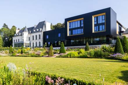 Façade du Domaine du Liziec mêlant architecture traditionnelle de manoir breton et design contemporain, entourée de jardins paysagers sous un ciel bleu