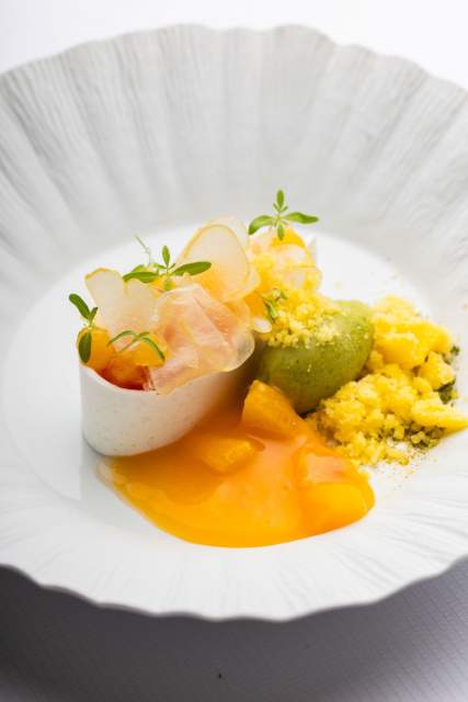 Assiette gastronomique au Domaine du Liziec avec composition végétale colorée, micro-pousses et sauce orange dans une présentation artistique